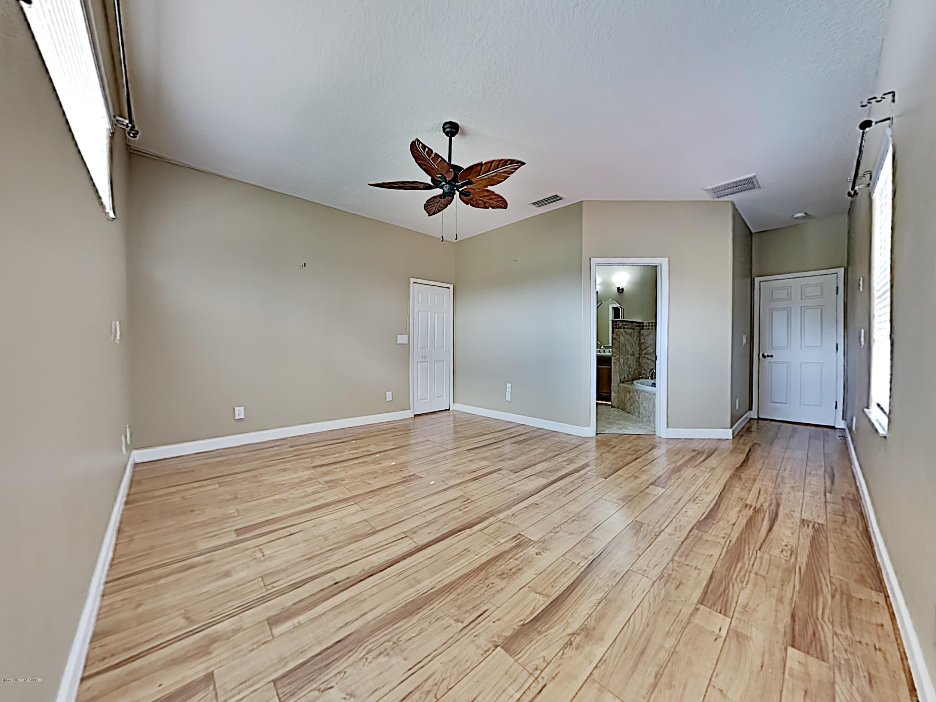 830 Riviera Drive Northeast Palm Bay, FL 32905 - Photo 9 of 21 a view of empty room with wooden floor and fan