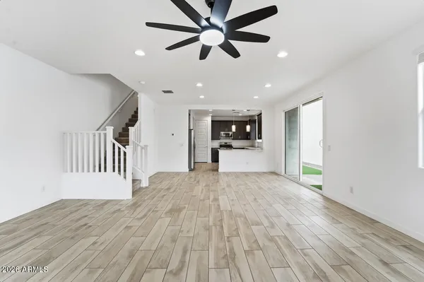 a view of a livingroom with a ceiling fan wooden floor and a ceiling fan