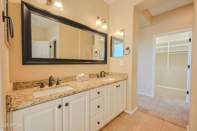 a bathroom with a granite countertop double vanity sink and a mirror