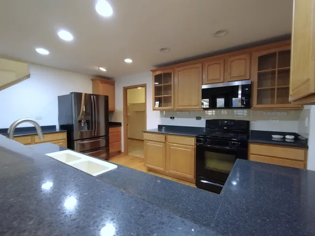 a kitchen with stainless steel appliances granite countertop a refrigerator and a stove top oven