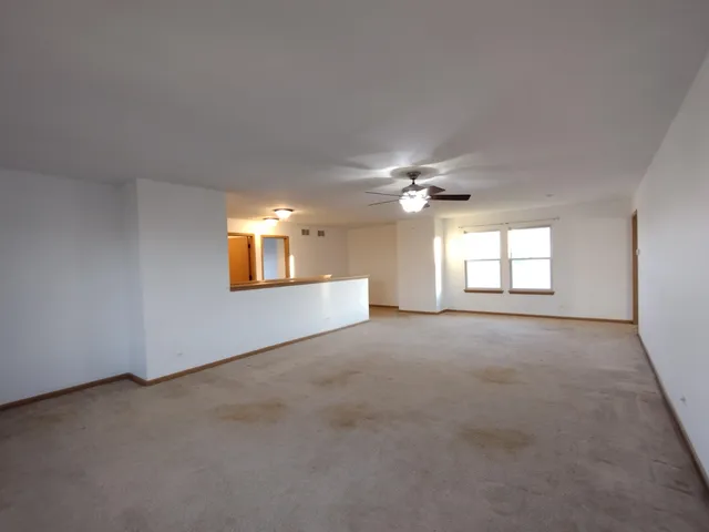 a view of a big room with windows and chandelier fan