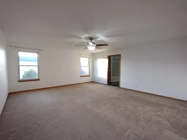 an empty room with windows and chandelier fan