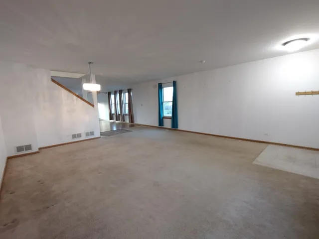 an empty room with stairs and entrance to other room