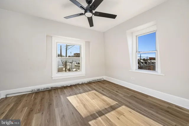 a view of an empty room with window and wooden floor