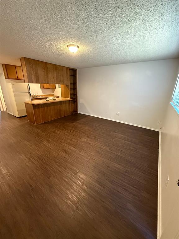 Open-concept living area featuring rich wood-finish flooring, white painted walls, and a built-in wood-paneled breakfast bar with integrated shelving