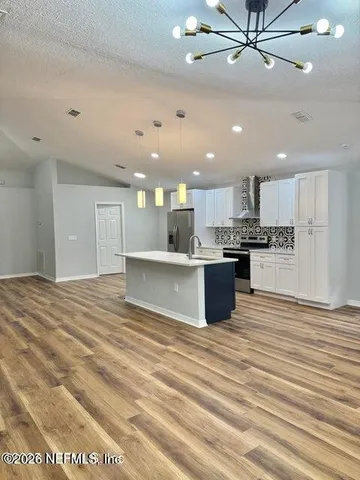a kitchen with granite countertop white cabinets and stainless steel appliances