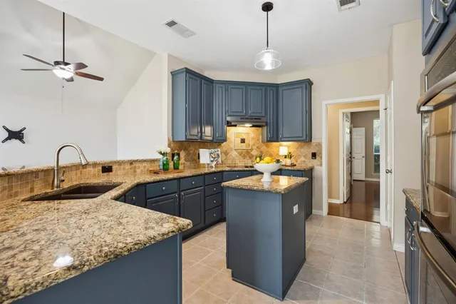 a kitchen with kitchen island granite countertop a sink stainless steel appliances and cabinets