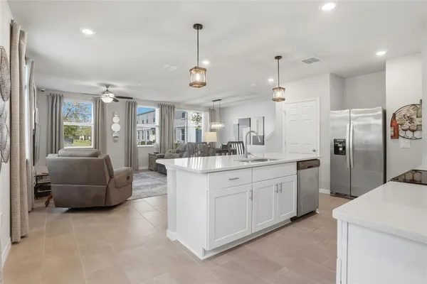 a kitchen with stainless steel appliances kitchen island granite countertop a dining table chairs and white cabinets