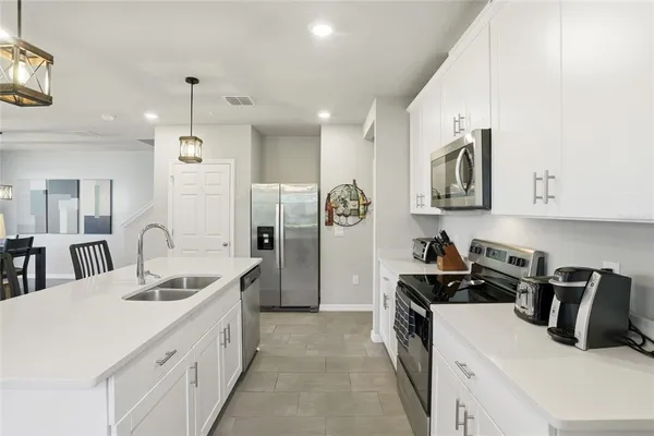 a kitchen with stainless steel appliances kitchen island granite countertop a dining table chairs and white cabinets