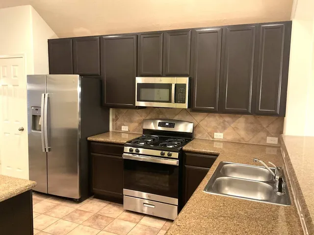 a kitchen with stainless steel appliances granite countertop a stove a refrigerator and a sink