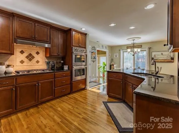 a kitchen with stainless steel appliances granite countertop wooden cabinets a stove top oven a sink and dishwasher