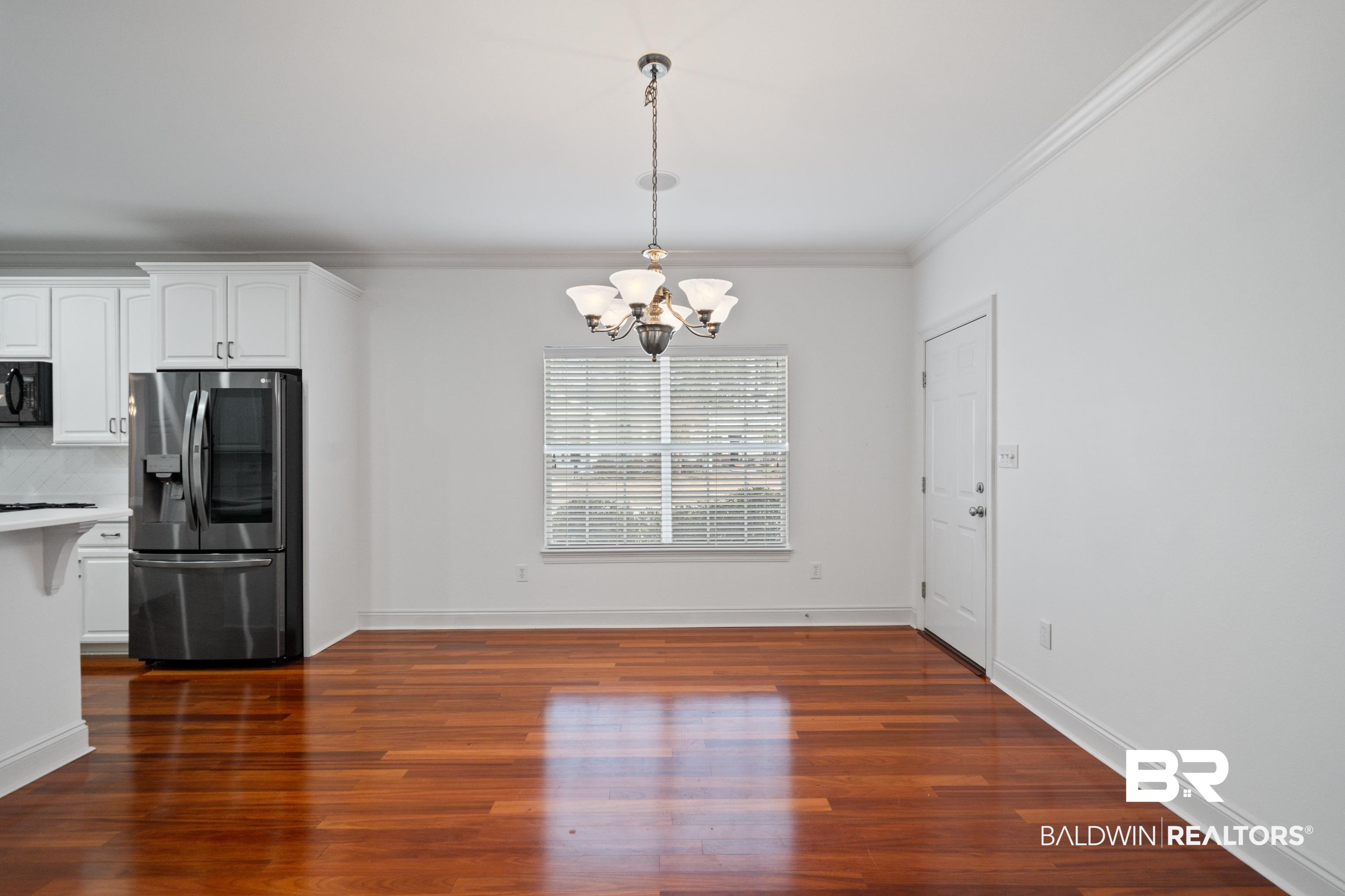 404 Savannah Lane Foley, AL 36535 - Photo 12 of 29 Unfurnished dining area with baseboards, ornamental molding, dark wood-style flooring, and an inviting chandelier