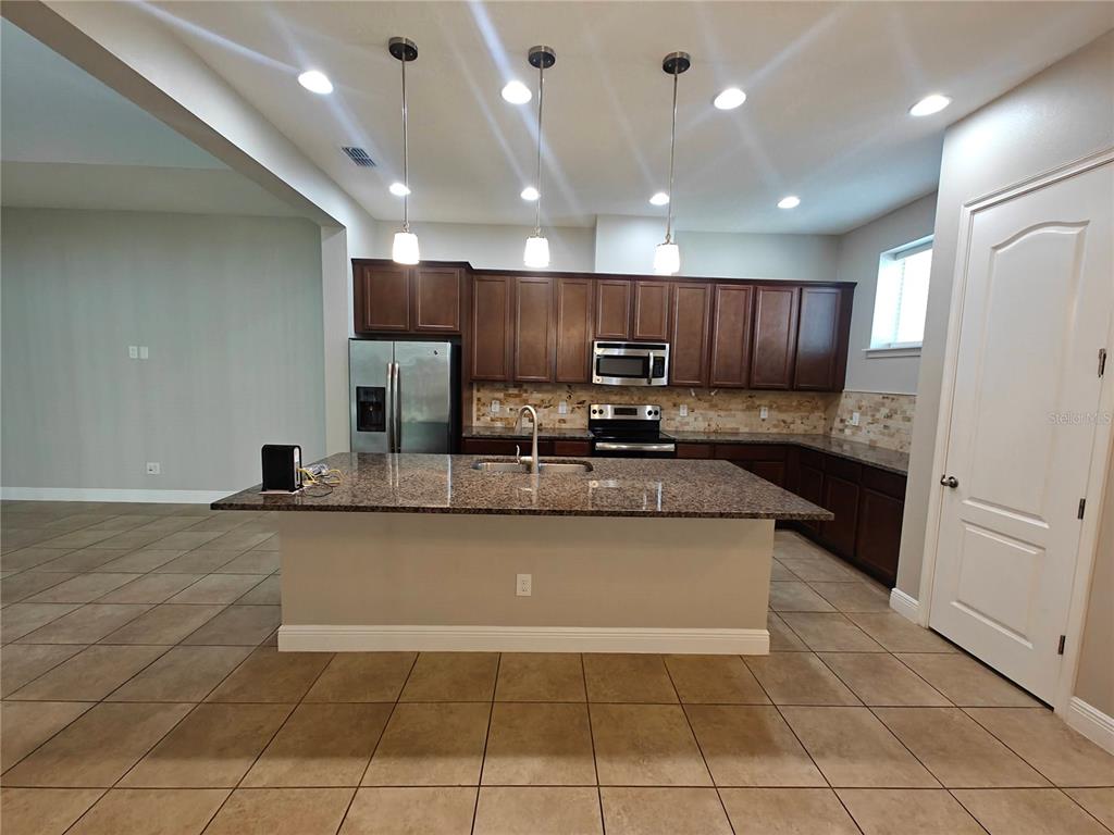 8075 Schelling Street Orlando, FL 32827 - Photo 2 of 51 a large kitchen with granite countertop a large counter top stainless steel appliances and cabinets