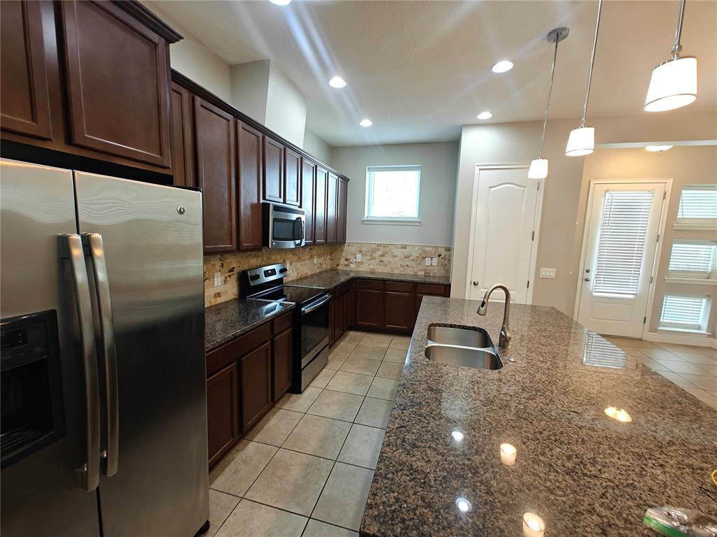 8075 Schelling Street Orlando, FL 32827 - Photo 4 of 51 a kitchen with granite countertop a refrigerator and a sink