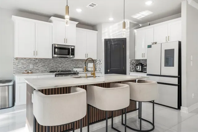 a kitchen with kitchen island a dining table chairs sink and microwave