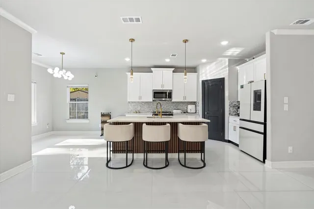 a large kitchen with stainless steel appliances kitchen island granite countertop a table chairs and a refrigerator