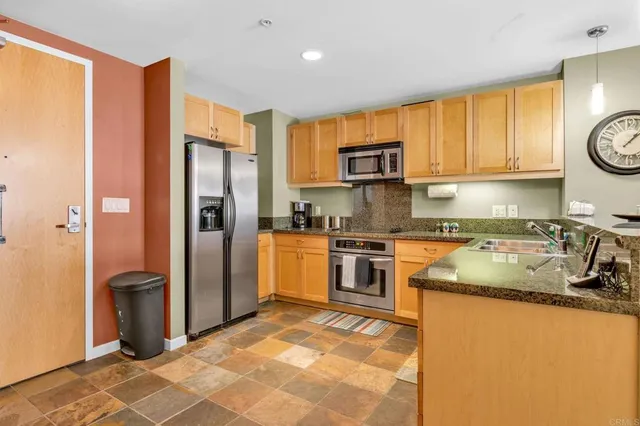 a kitchen with granite countertop a refrigerator a stove top oven a sink and dishwasher