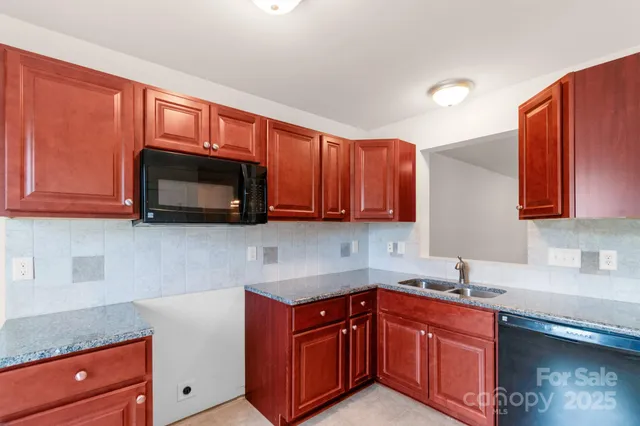 a kitchen with stainless steel appliances granite countertop wooden cabinets a stove a sink and a microwave