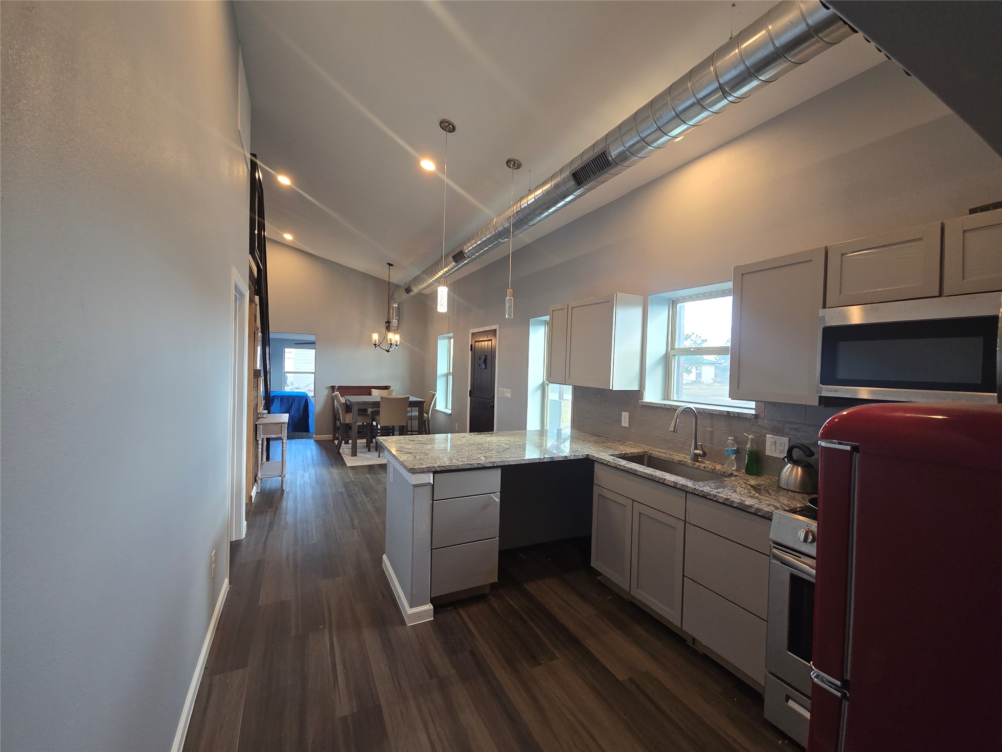 304 Spring Street Burnet, TX 78611 - Photo 6 of 11 Kitchen with a peninsula, stainless steel appliances, light stone countertops, pendant lighting, and decorative backsplash