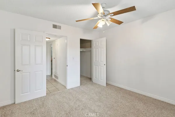 an empty room with closet and a ceiling fan