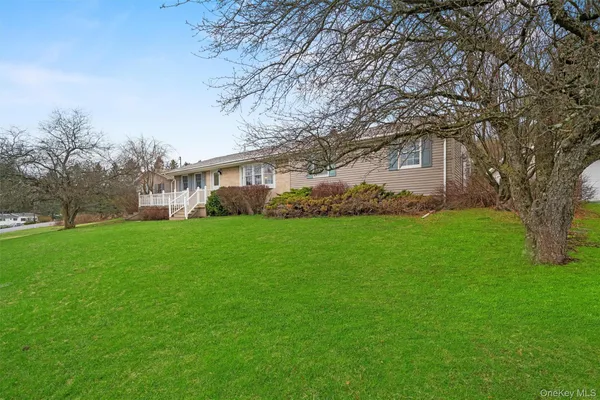 a white house with a big yard and large trees