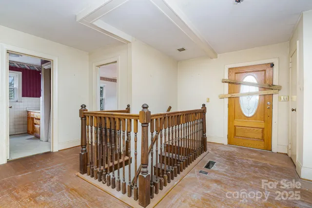 an empty room with chandelier fan and windows