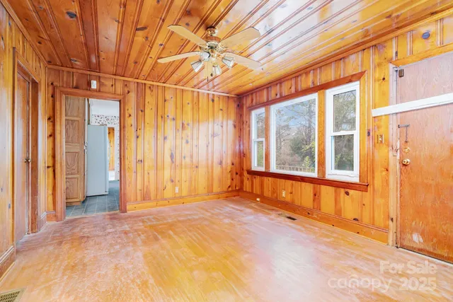 a view of empty room with wooden floor and fan