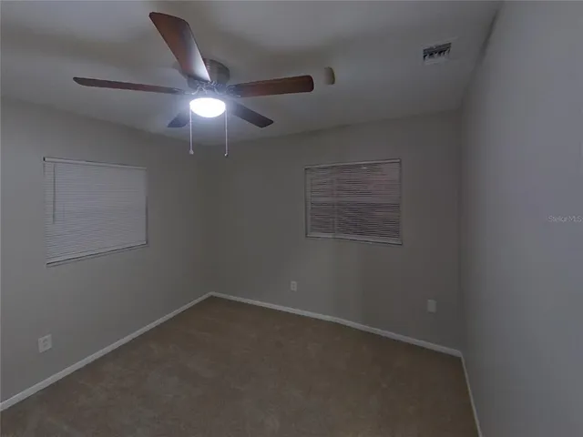 an empty room with a ceiling fan and a window