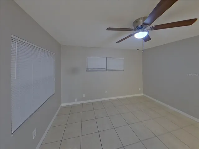 an empty room with white walls and ceiling fan