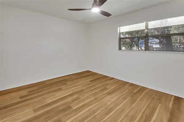 a view of empty room with wooden floor and fan