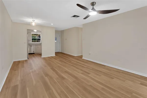 a view of empty room with wooden floor and fan