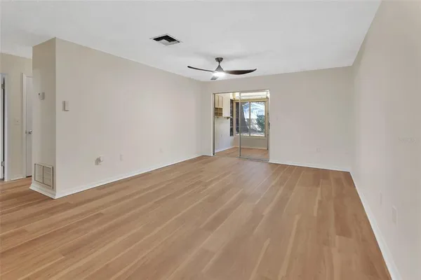 a view of empty room with wooden floor and ceiling fan