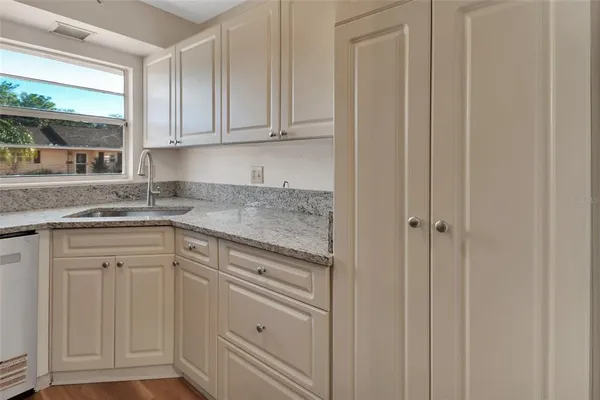 a kitchen with granite countertop white cabinets and sink