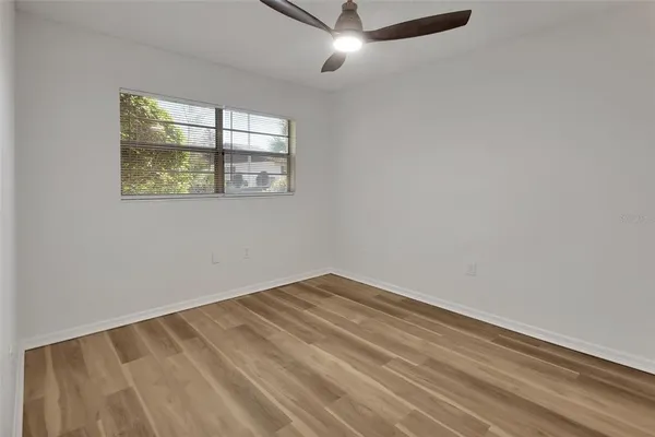 an empty room with window and ceiling fan