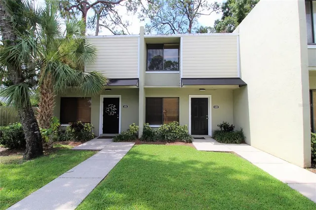 a view of a brick house with a large windows and a yard with plants and large trees