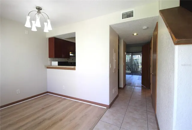 a view of a hallway with wooden floor and chandelier