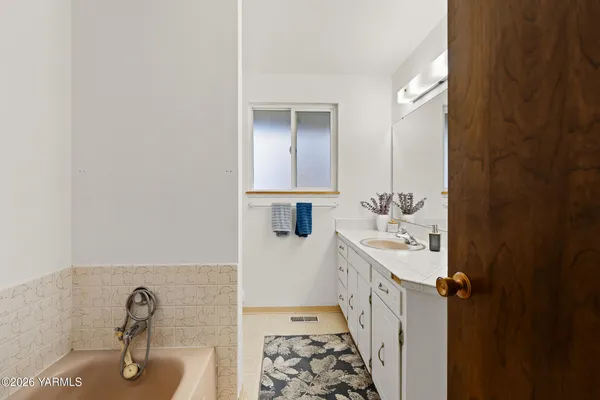 a bathroom with a sink and mirror with bathtub