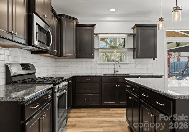 a kitchen with stainless steel appliances granite countertop a stove a sink and a microwave