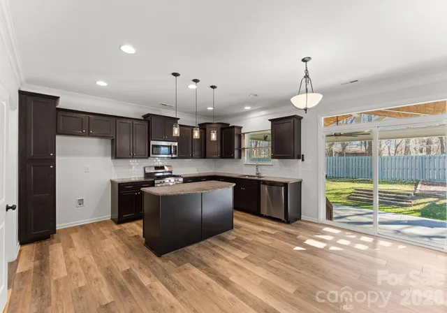 a kitchen with stainless steel appliances kitchen island granite countertop a refrigerator and a sink