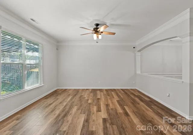 a view of empty room with wooden floor and fan