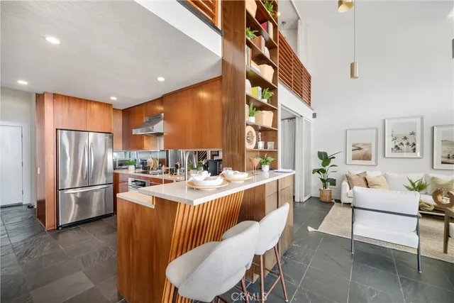 a kitchen with stainless steel appliances granite countertop a refrigerator a sink dishwasher a dining table and chairs with wooden floor