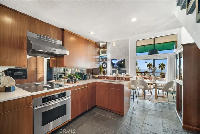 a kitchen with stainless steel appliances a stove a sink a oven a dining table and chairs