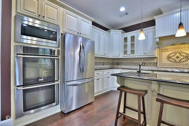a kitchen with stainless steel appliances granite countertop a sink a stove cabinets and wooden floor
