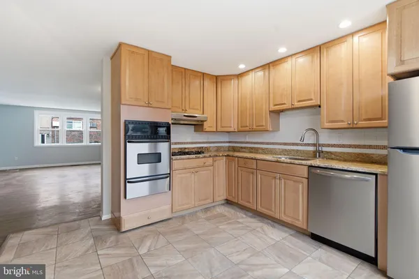 a kitchen with stainless steel appliances granite countertop a stove a sink and a refrigerator