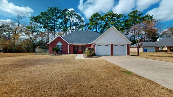 a front view of house with yard and trees in the background