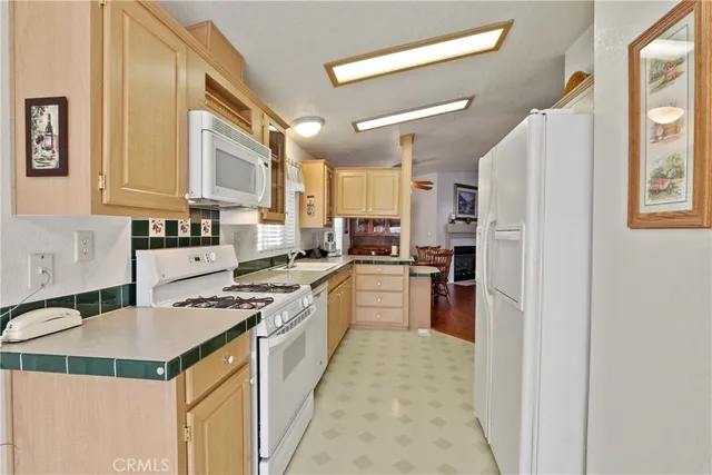 a kitchen with a refrigerator a stove top oven a sink dishwasher and white cabinets with wooden floor