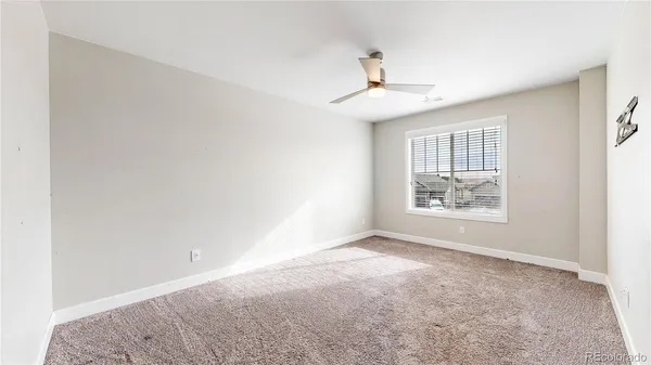 an empty room with windows and ceiling fan
