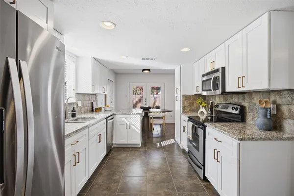 a kitchen with white cabinets and appliances
