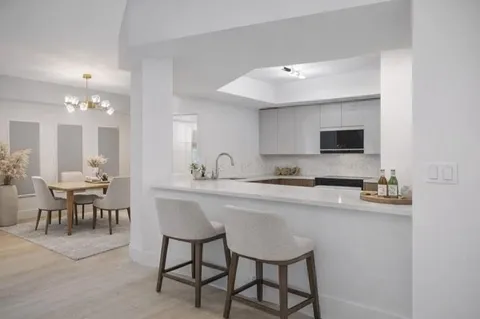 a kitchen with stainless steel appliances granite countertop a refrigerator a stove top oven a sink dishwasher and white cabinets with wooden floor