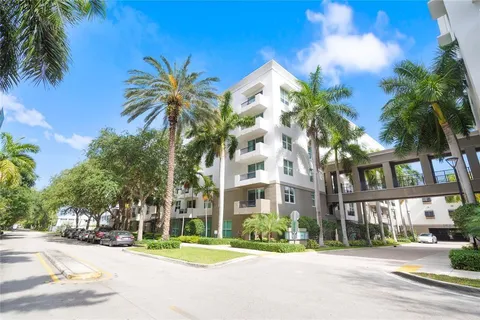 a view of multiple houses with a yard and palm trees